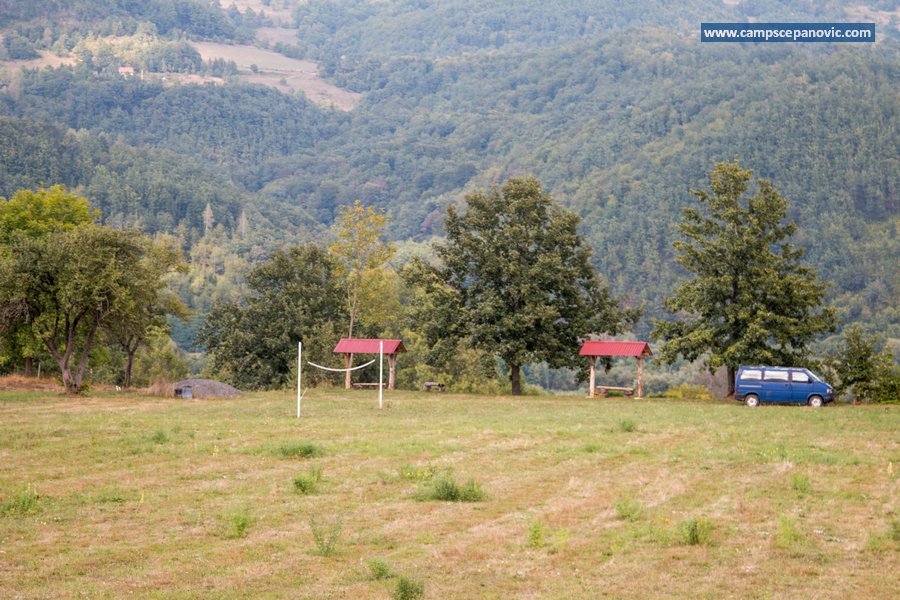 Open camping field with volleyball posts and mountain backdrop