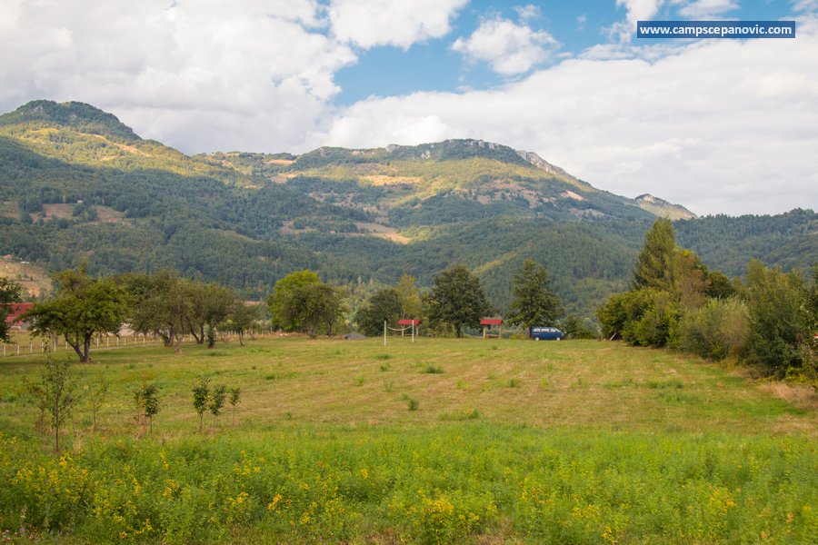 Large grassy camping area below the mountains
